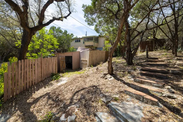 a view of a backyard with large trees and wooden fence