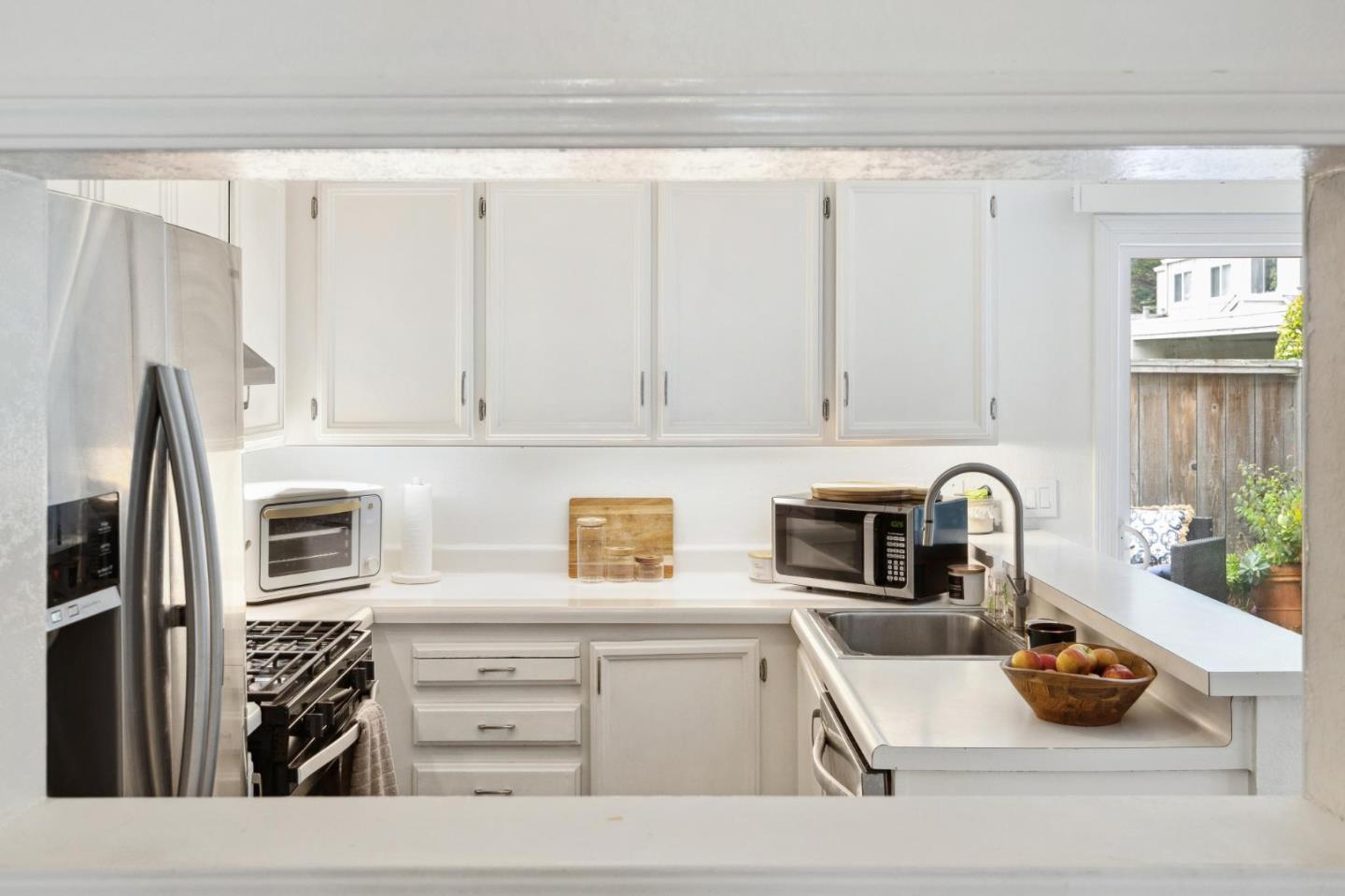 1287 Rosita Road Pacifica, CA 94044 - Photo 23 of 76 a kitchen with stainless steel appliances granite countertop a sink and white cabinets