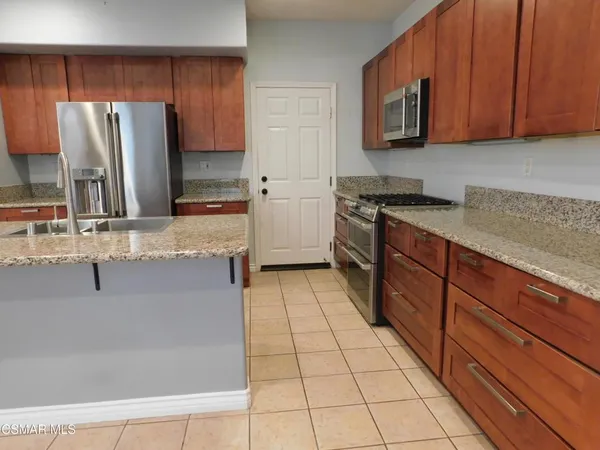 a kitchen with stainless steel appliances granite countertop a refrigerator a stove and a sink