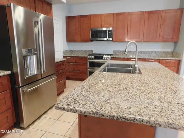 a kitchen with stainless steel appliances granite countertop a refrigerator oven a sink a stove and white cabinets