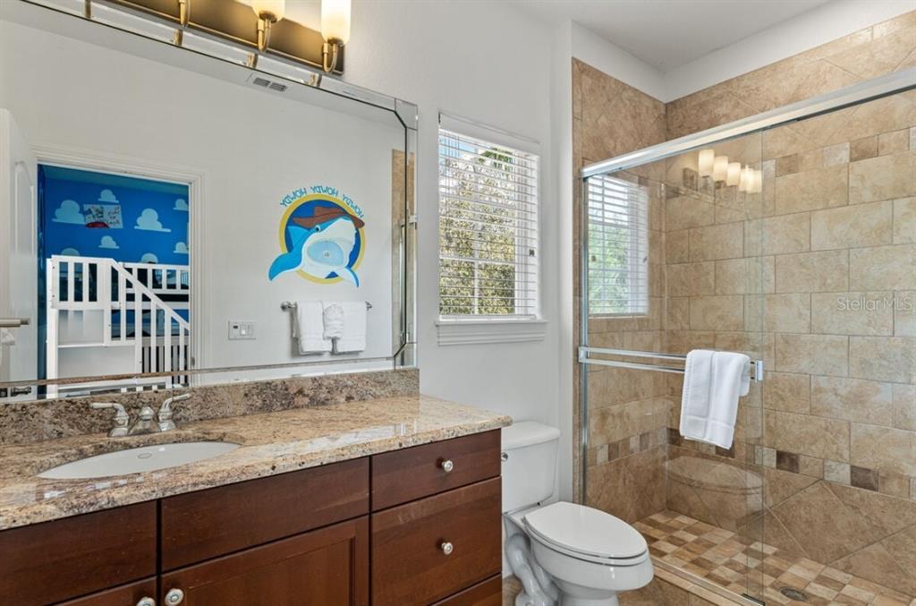 1227 Radiant Street Reunion, FL 34747 - Photo 50 of 70 a bathroom with a granite countertop sink a toilet a mirror a vanity and shower