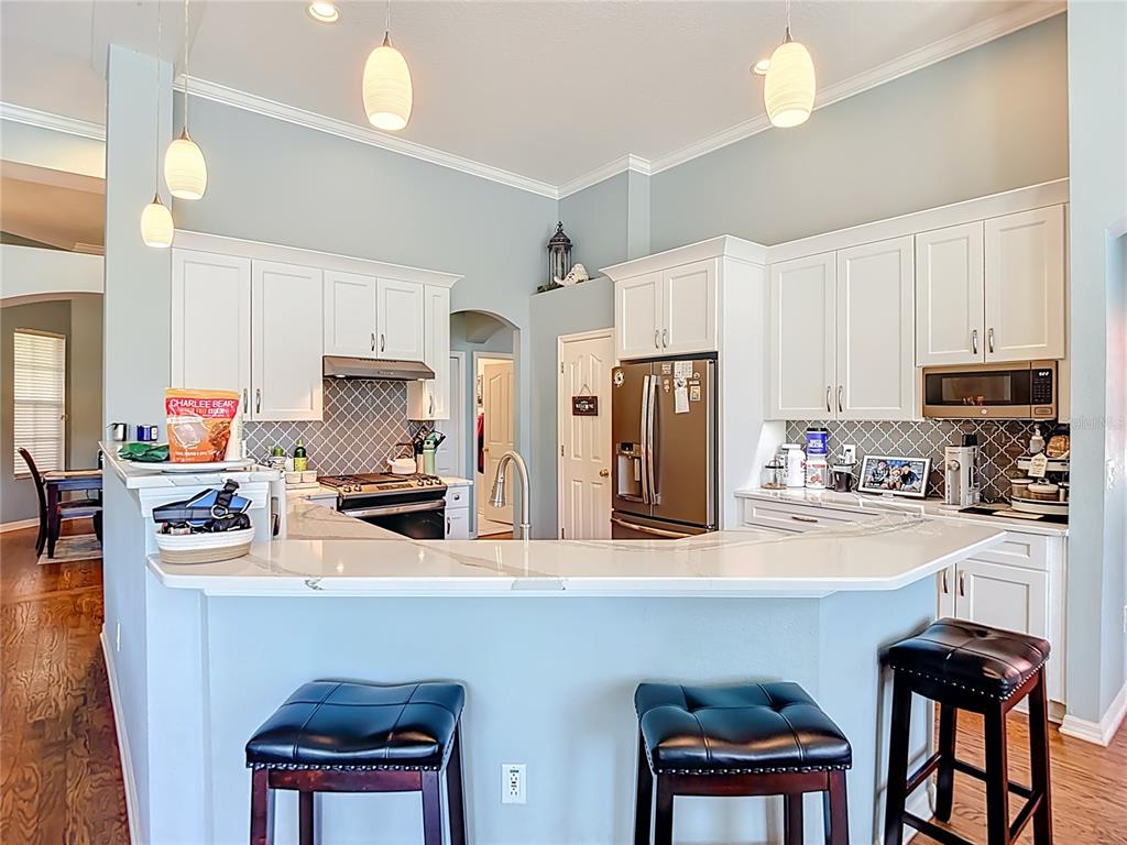 4805 Tea Rose Court Lutz, FL 33558 - Photo 17 of 59 a kitchen with stainless steel appliances a refrigerator a stove a sink dishwasher and white cabinets with wooden floor