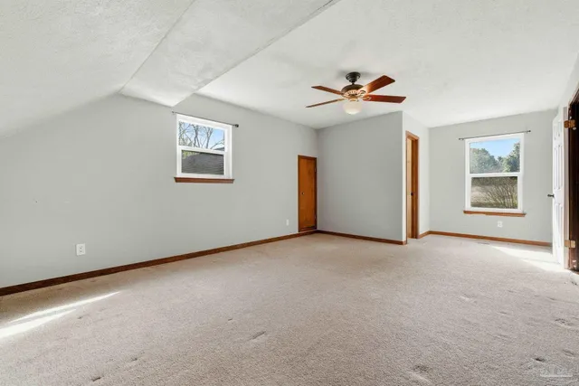 an empty room with windows and ceiling fan