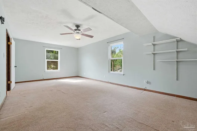 an empty room with windows and ceiling fan