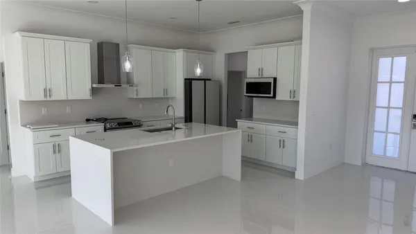 a kitchen with stainless steel appliances granite countertop a sink a stove a refrigerator cabinets and dining table with wooden floor