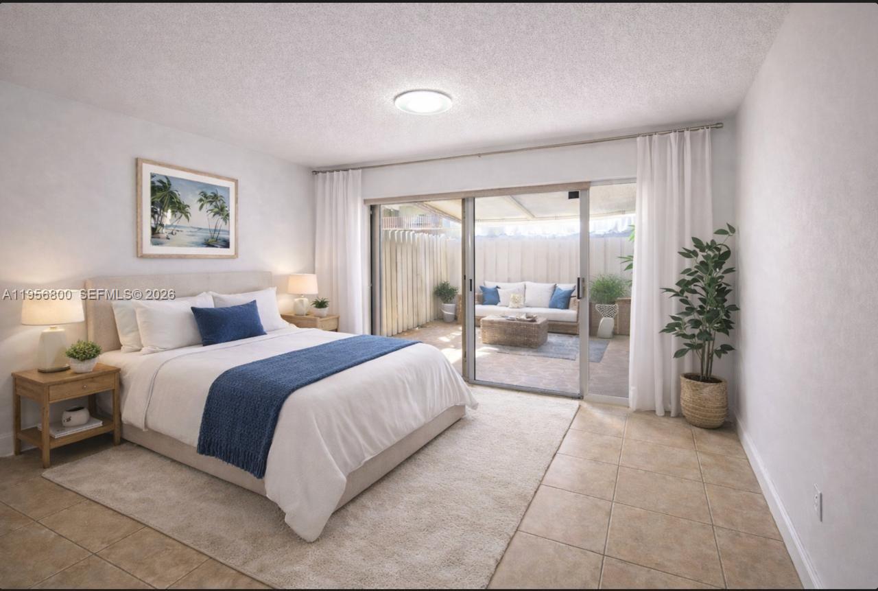 850 Southwest 129th Place, Unit 103 Miami, FL 33184 - Photo 4 of 8 a spacious bedroom with a bed and a large window