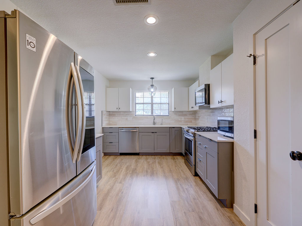 5842 Secrest Drive Austin, TX 78759 - Photo 37 of 40 A well-lit kitchen featuring stainless steel appliances and wood-look flooring.