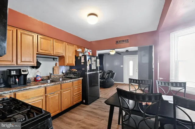 a kitchen with stainless steel appliances granite countertop a stove top oven a sink dishwasher a dining table and chairs with wooden floor