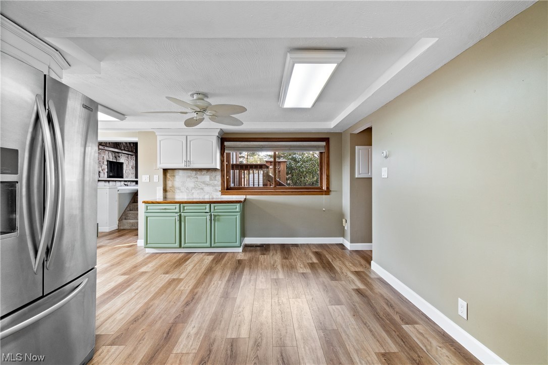 2921 Sanitarium Road Akron, OH 44312 - Photo 16 of 30 Kitchen with stainless steel fridge with ice dispenser, light hardwood / wood-style floors, backsplash, and ceiling fan