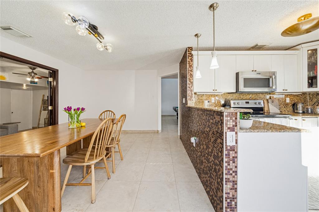 14277 Southwest 177th Street Miami, FL 33177 - Photo 11 of 38 a kitchen with stainless steel appliances kitchen island granite countertop a table and chairs in it