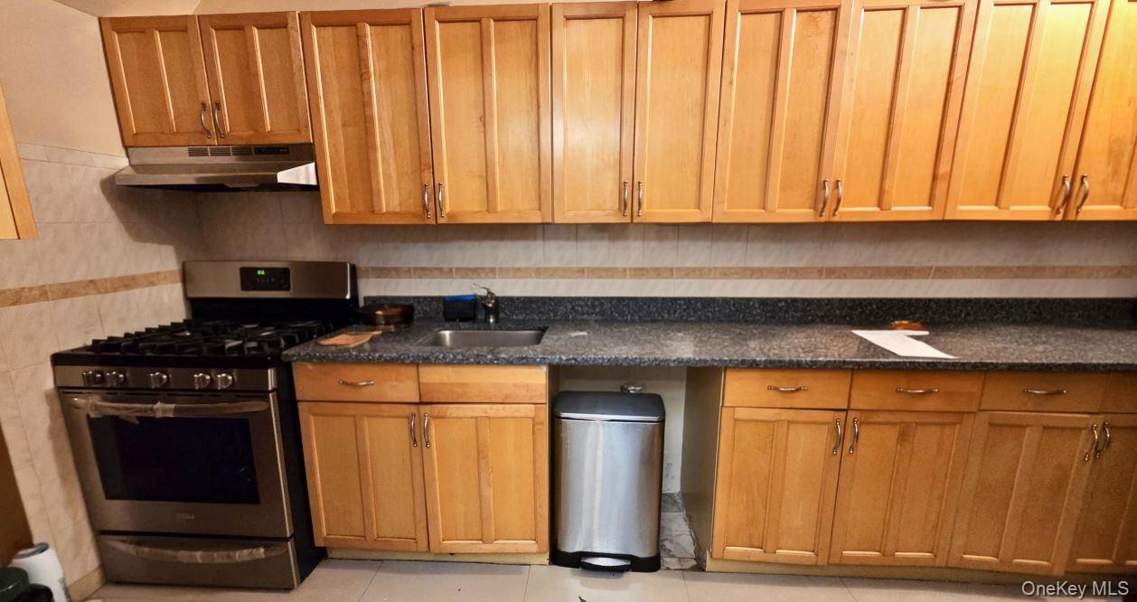 25-55 97th Street Queens, NY 11369 - Photo 10 of 15 a kitchen with granite countertop cabinets and black appliances