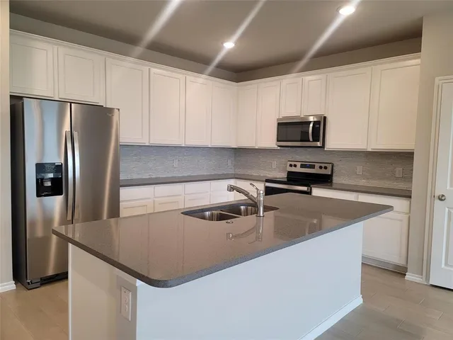 a kitchen with kitchen island a sink dishwasher a refrigerator and a stove