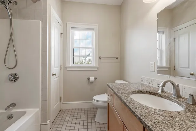 a bathroom with a granite countertop sink a toilet and shower