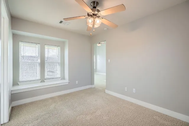 an empty room with a window and a fan