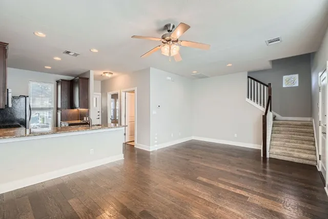a view of a kitchen with a sink a refrigerator a ceiling fan and wooden floor