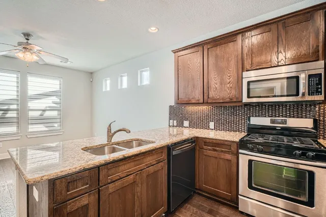 a kitchen with granite countertop a sink cabinets stainless steel appliances and window