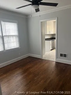 an empty room with wooden floor cabinet and windows