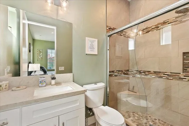 a bathroom with a granite countertop sink a toilet a mirror and shower