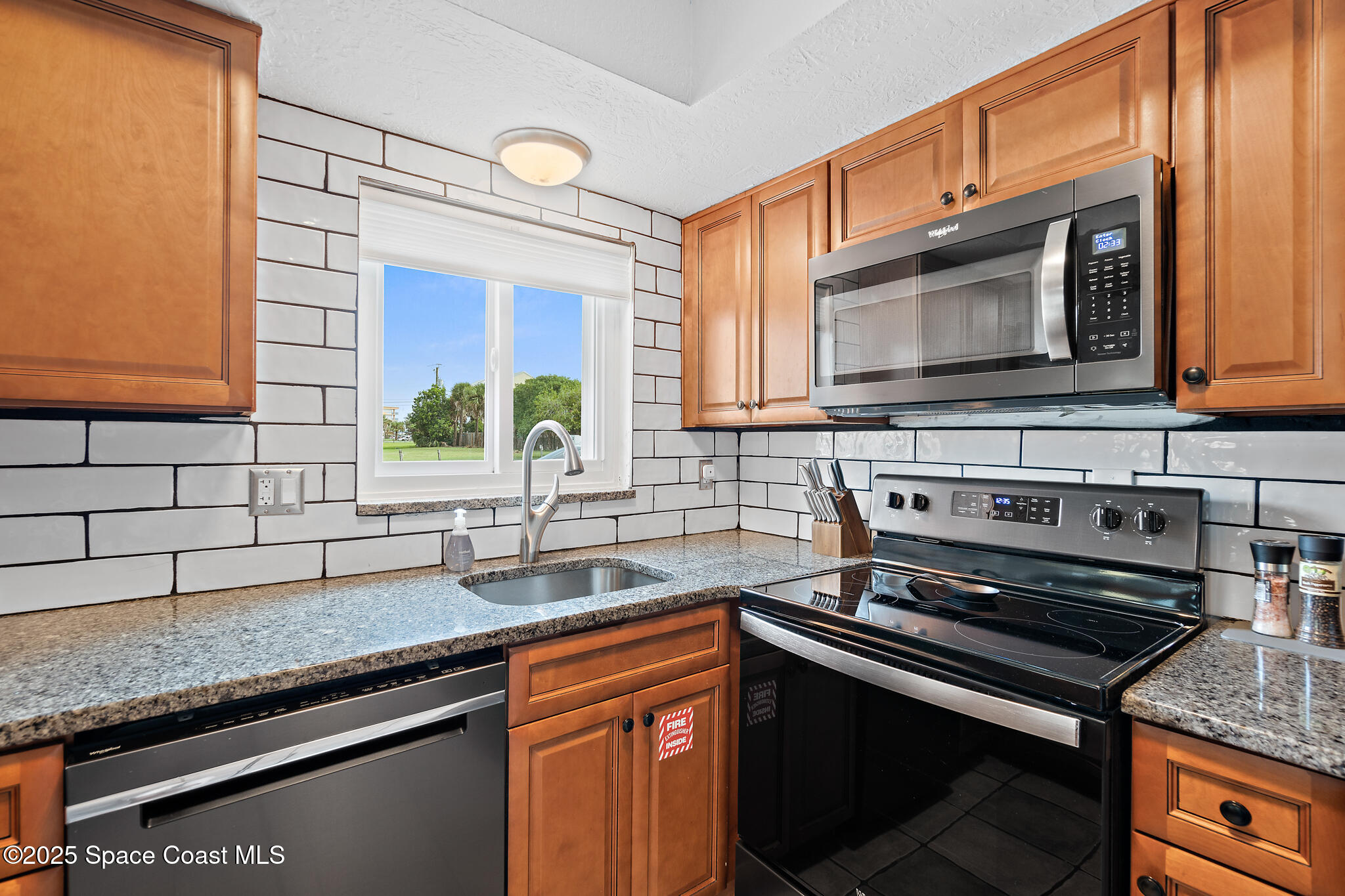 8156 Ridgewood Avenue Cape Canaveral, FL 32920 - Photo 25 of 53 a kitchen with stainless steel appliances granite countertop a sink stove and microwave