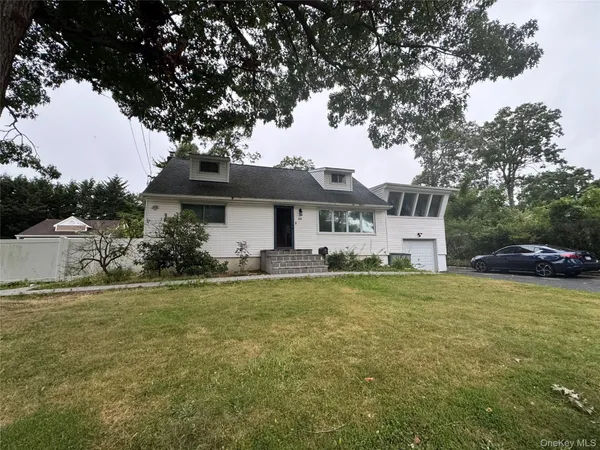a front view of a house with a garden and tree