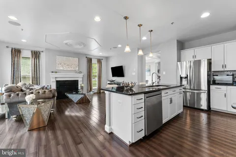 a large kitchen with stainless steel appliances kitchen island granite countertop a stove and a wooden floors