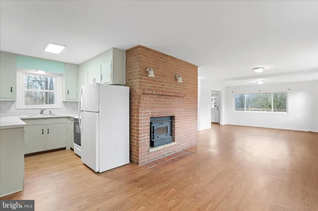 a kitchen with a refrigerator a stove top oven and wooden floors