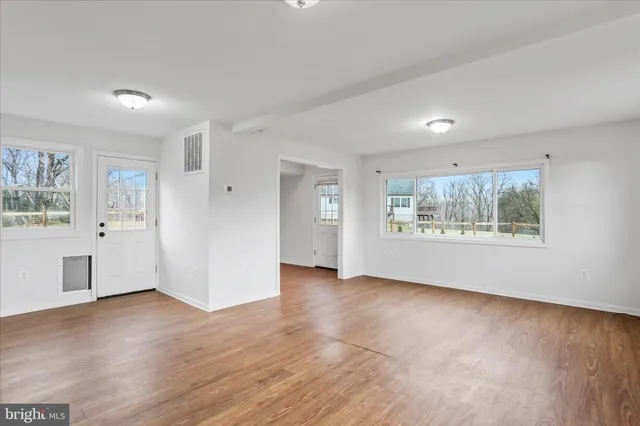 a view of an empty room with a window and wooden floor