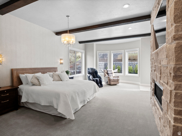 614 East High Lane Alpine, UT 84004 - Photo 44 of 75 Bedroom with carpet, beamed ceiling, multiple windows, a stone fireplace, and a chandelier