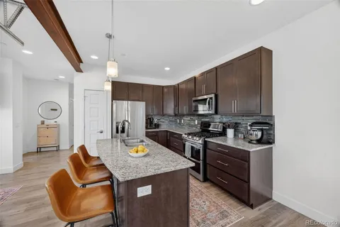 a kitchen with stainless steel appliances granite countertop a sink stove and refrigerator