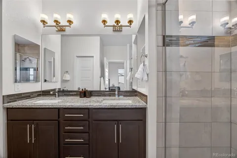 a bathroom with a granite countertop sink a mirror and a shower