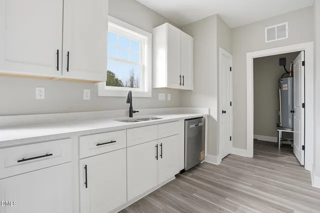 a kitchen with white cabinets and sink