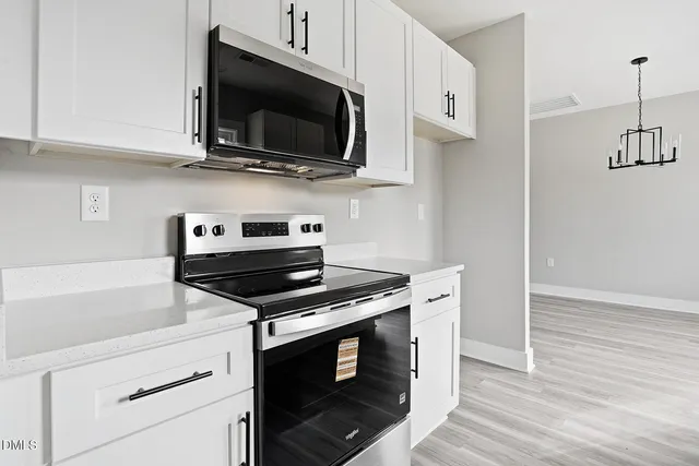 a kitchen with cabinets stainless steel appliances and wooden floor