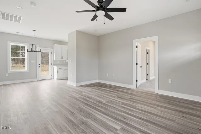 a view of empty room with wooden floor and ceiling fan