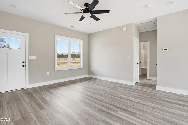 a view of an empty room with wooden floor and a window