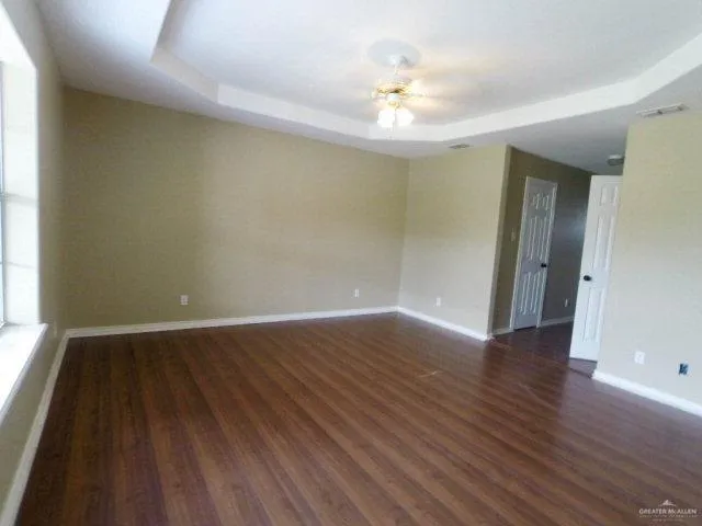 an empty room with wooden floor and chandelier fan