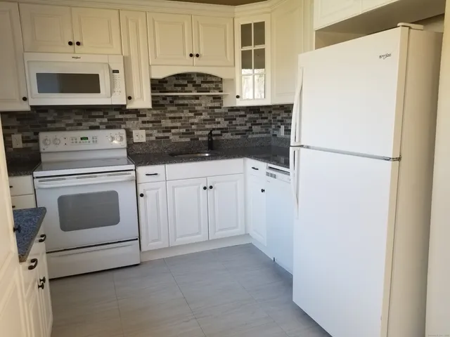 a kitchen with cabinets appliances a sink and a window
