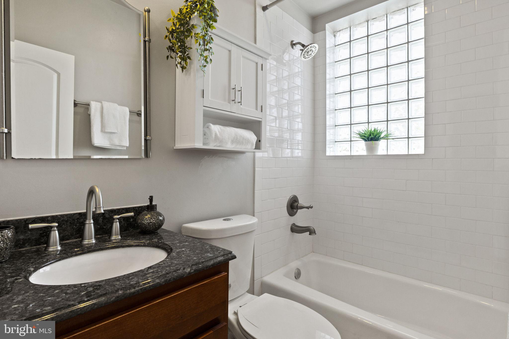 410 15th Street Northeast, Unit 22 Washington, DC 20002 - Photo 13 of 27 a bathroom with a granite countertop sink a toilet a mirror and bathtub