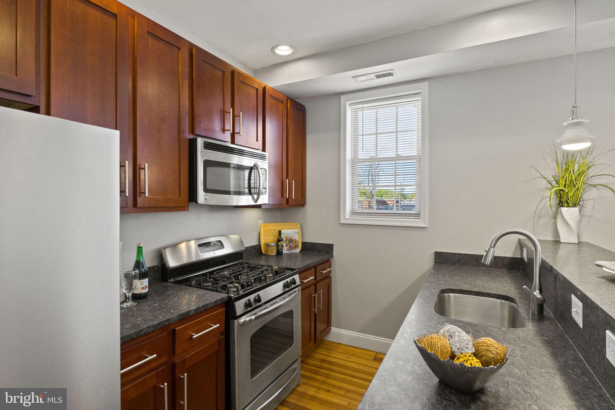 410 15th Street Northeast, Unit 22 Washington, DC 20002 - Photo 4 of 27 a kitchen with stainless steel appliances granite countertop a stove a sink and a microwave