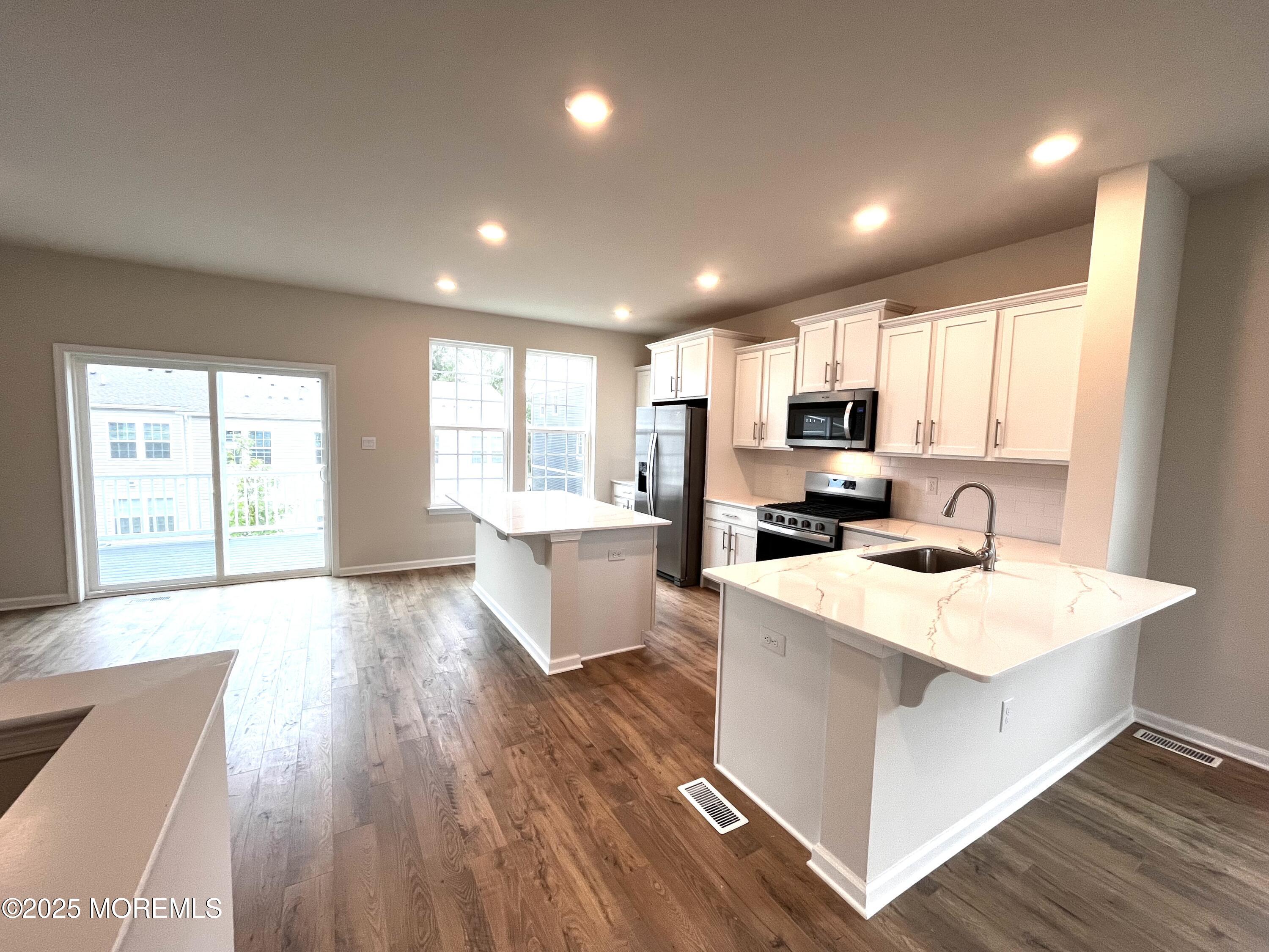 16 Rothbury Court Tinton Falls, NJ 07753 - Photo 2 of 28 a large kitchen with kitchen island a sink wooden floor and white cabinets