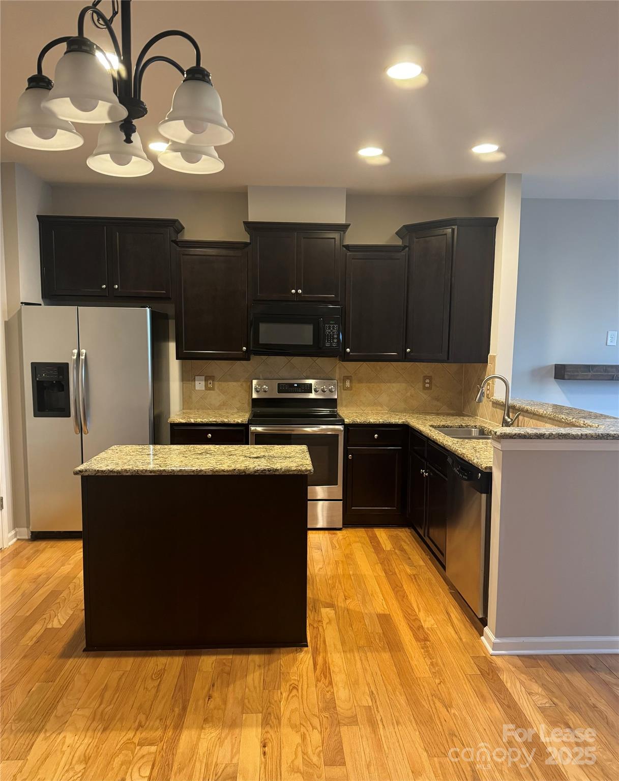 18431 The Commons Boulevard Cornelius, NC 28031 - Photo 3 of 24 a kitchen with kitchen island granite countertop a stove and a sink