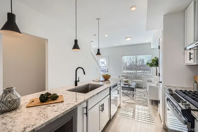 a kitchen with granite countertop a sink a stove and a wooden floor