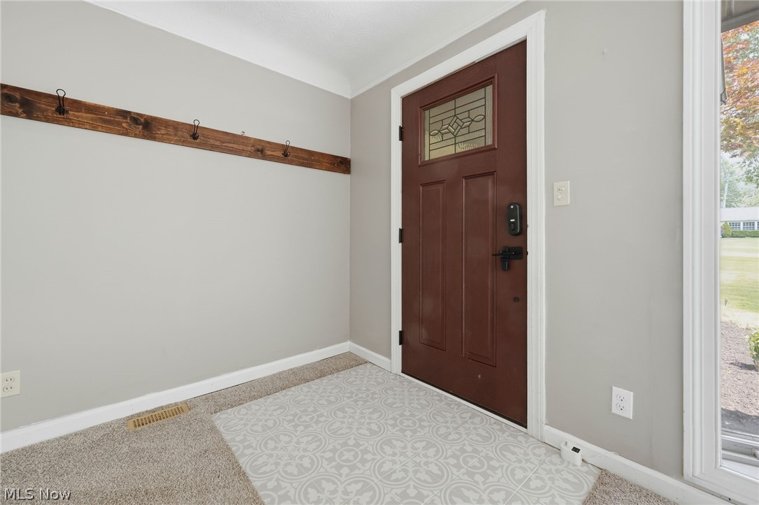 8160 Joyce Road Broadview Heights, OH 44147 - Photo 8 of 45 Entryway featuring a rich brown door with decorative glass inserts, light gray walls, white trim, and a built-in wooden coat rack