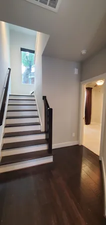 a view of a livingroom with wooden floor and stairs