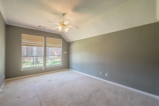 an empty room with a ceiling fan and window