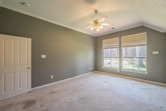 an empty room with chandelier fan and windows