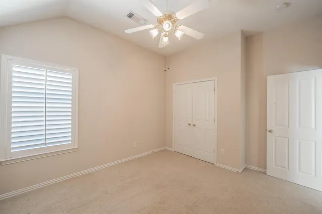 an empty room with windows and fan