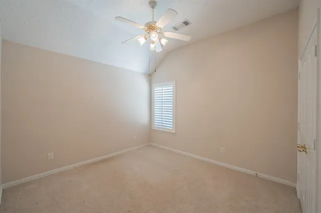 an empty room with windows and chandelier fan