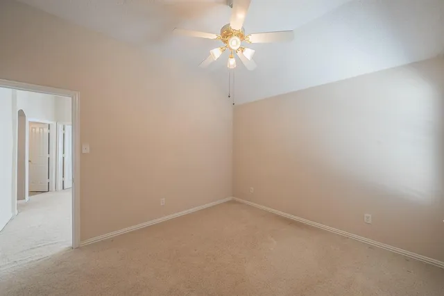 an empty room with a chandelier fan and windows