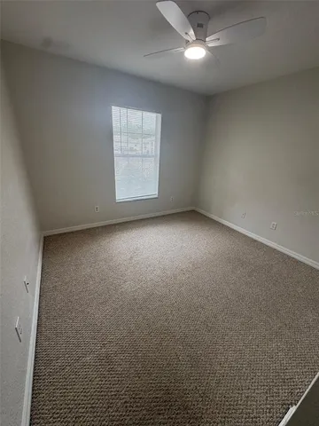 an empty room with a ceiling fan and window