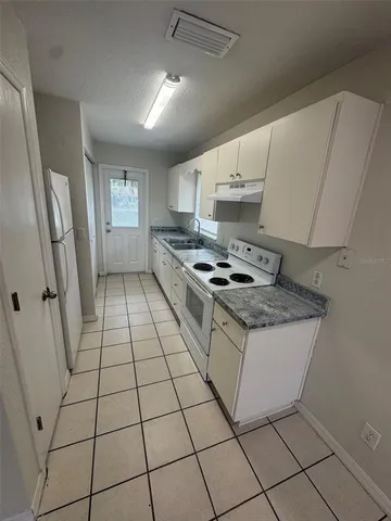 a kitchen with granite countertop a stove a sink and a refrigerator